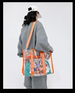 Rear view of a model wearing the large transparent PVC tote bag with orange straps