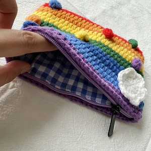 Detail of rainbow crochet pouch with white cloud decor and blue checkered lining