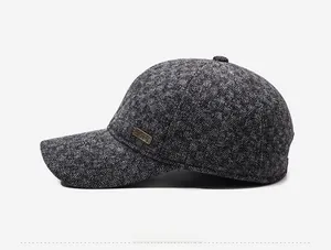 Detail view of the deep gray wool blend fabric and metal logo plaque on a winter baseball cap