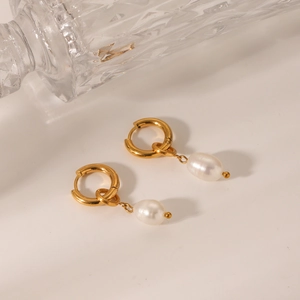 Detailed close-up of gold hoop earrings featuring elegant white freshwater pearl pendants
