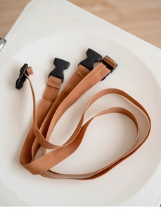 Detail of durable brown nylon safety harness straps with black plastic buckles on tray