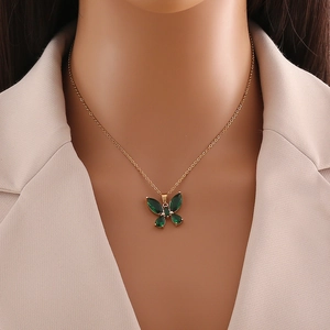 Close-up of elegant gold butterfly necklace featuring four emerald green gemstones on model
