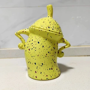 Detail of yellow ceramic canister with unique handles and blue speckled pattern