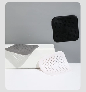 Tre filtri per lavello quadrati in silicone nero grigio e bianco su supporto moderno
