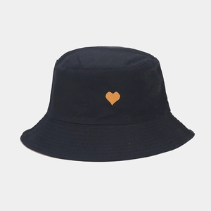 Détail d'un chapeau bob noir avec une petite broderie de cœur orange sur tissu en coton pur