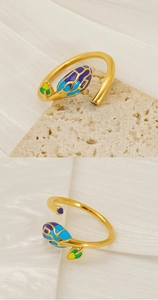 Detail of golden adjustable ring with colorful floral enamel pattern on stone backdrop