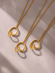 Close-up of three 18k gold irregular double loop knot necklaces on a beige background