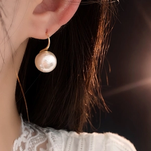 Gros plan d'une boucle d'oreille élégante plaquée or avec perle blanche ronde sur mannequin