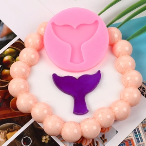 Pink silicone mold for mermaid tail cake toppers with a purple finished resin tail piece