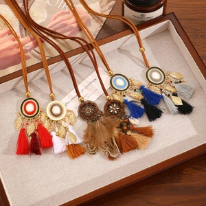 Detalle de collares bohemios con borlas, plumas y colgantes esmaltados en bandeja
