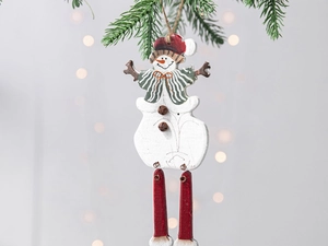 Detail of wooden snowman ornament with metal bells and hanging legs on pine branch