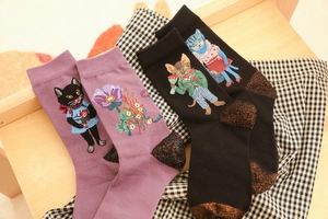 Detail of purple and black cotton socks featuring embroidered cat patterns and sequins