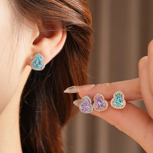 Close-up of sparkling gourd earrings in gold and silver with blue and pink cubic zirconia