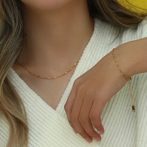 Dettaglio del set collana e bracciale dorati con maglia a onde indossati da una modella