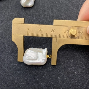 Macro detail of natural freshwater baroque pearl pendant measured with a brass caliper
