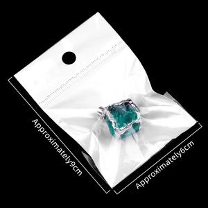 Green crystal stone pendant with silver metal edge and size markings on black background