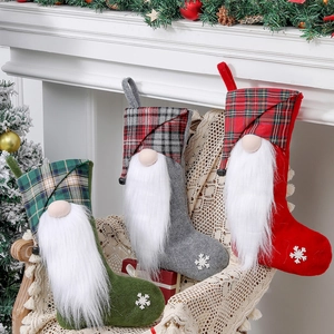 Three Christmas stockings with gnomes and plaid patterns in red, green, and gray on a chair