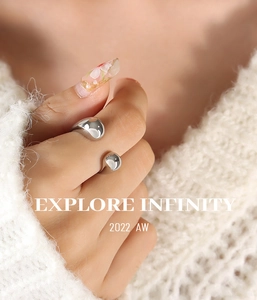 Detail view of silver liquid metal style ring worn on hand with knitted sweater background