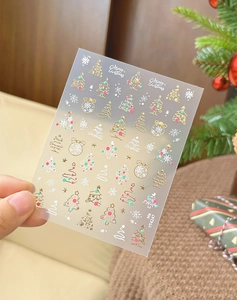 Detail of Christmas nail stickers with gold trees and snowflakes for manicure art