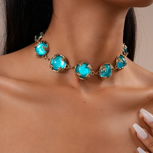 Gros plan d'un choker vintage avec maillons dorés et pierres circulaires en résine bleue