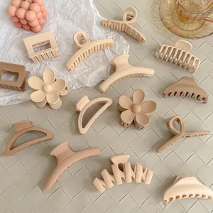 Flat lay of matte milk tea colored large hair claws in various flower and geometric shapes