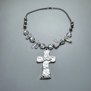 Detailed view of silver cross pendant with hammered texture and crystal beaded chain