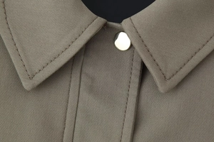 Close-up of lapel collar with gold metal button on coffee-colored bomber jacket