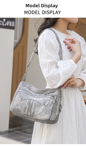 Grey vintage soft leather shoulder bag with multi-zipper pockets worn by a model