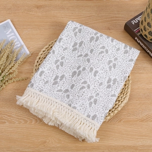 Detail of baby tassel blanket with grey leaf patterns and cream fringe on cotton gauze