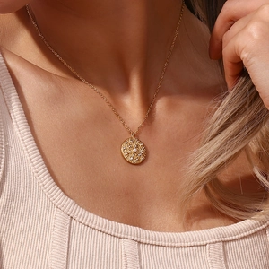 Dettaglio di una collana dorata con ciondolo di perla e zirconi indossata da una modella