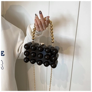 Detail of black bubble texture acrylic handbag with large gold pearl handle and gold chain