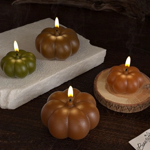 Close-up of decorative pumpkin candles in autumn colors on rustic wood and stone bases