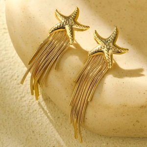Elegant gold starfish earrings with long tassel snake chains on a ceramic background
