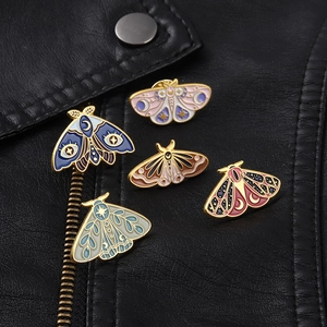 Detail of moth enamel pins with celestial patterns on a black leather jacket