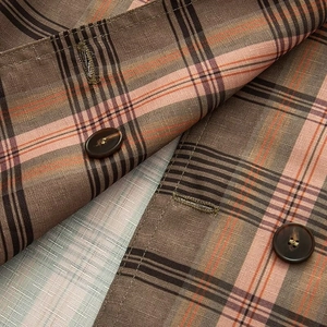Close-up of classic brown and pink plaid fabric texture with amber pattern buttons