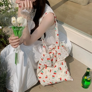Detail of canvas tote bag with cherry print and bow decoration in outdoor lifestyle setting