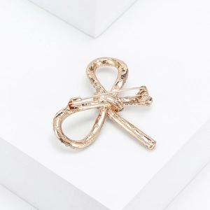 Detail of gold bow brooch back showing secure pin fastener and metal texture