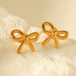 Elegant 18k gold plated stainless steel bow earrings on white textured stone background