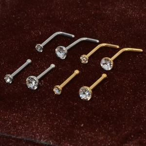 Macro shot of silver and gold L-shaped and straight nose studs with clear crystals