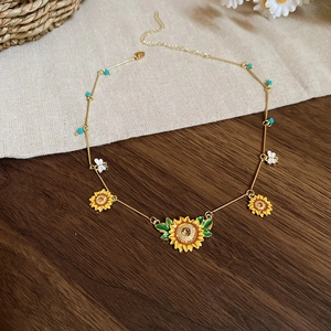 Detail of sunflower necklace with bee charms and colorful beads on a rustic table