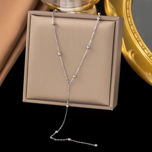 Macro shot of silver beaded chain necklace hanging on a display box with dark background