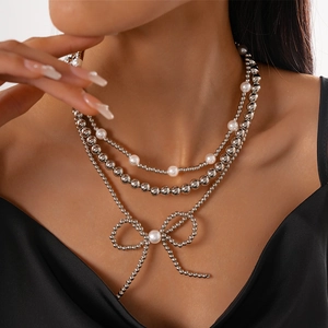 Detailed close-up of a three-layer beaded necklace featuring pearls and a bow pendant