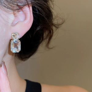 Close-up of model wearing geometric crystal earrings with gold plating and studs