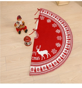 Detail of red knitted Christmas tree skirt featuring white reindeer and Merry Christmas text