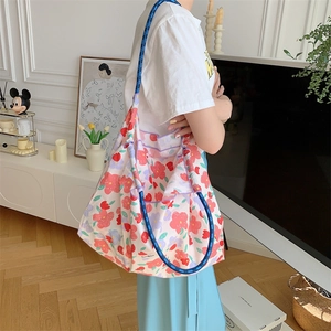 Macro view of floral tote bag with blue rope handle and vivid flower patterns on canvas