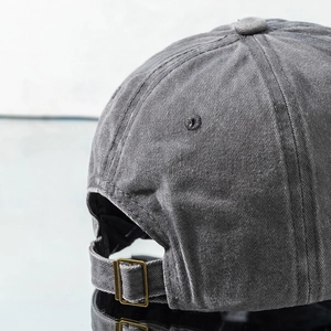 Detail of washed cotton baseball cap featuring adjustable metal buckle and grey fabric texture