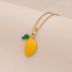 Dettaglio di un ciondolo a forma di mango giallo su catena dorata con foglia verde