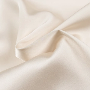 Close-up of beige satin fabric showing smooth texture and elegant glossy finish