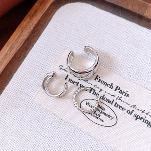 Set of three silver-plated zircon ear cuffs displayed on a vintage fabric background prop.