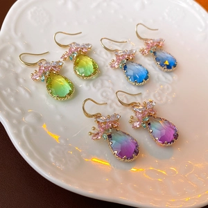Vue détaillée de boucles d'oreilles goutte en zircon dégradé sur un plateau en céramique